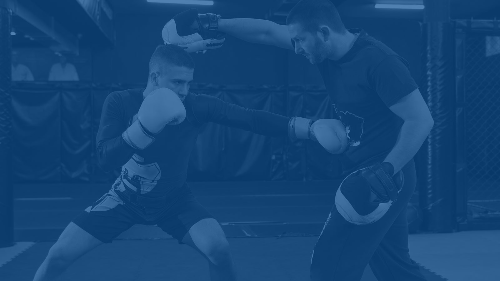 Two people practicing mixed martial arts sparring drills.