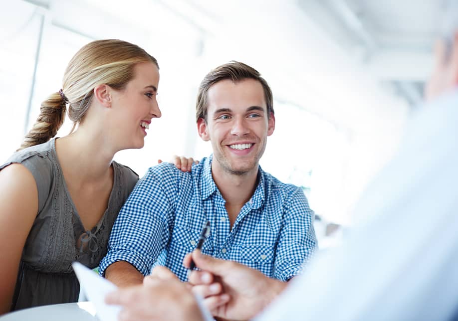 Young couple smiling while meeting with advisor in bright modern office
